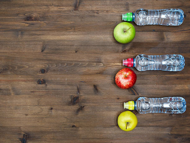 istock . three colored Apples and sport  water bottles on  wooden table 490238228
