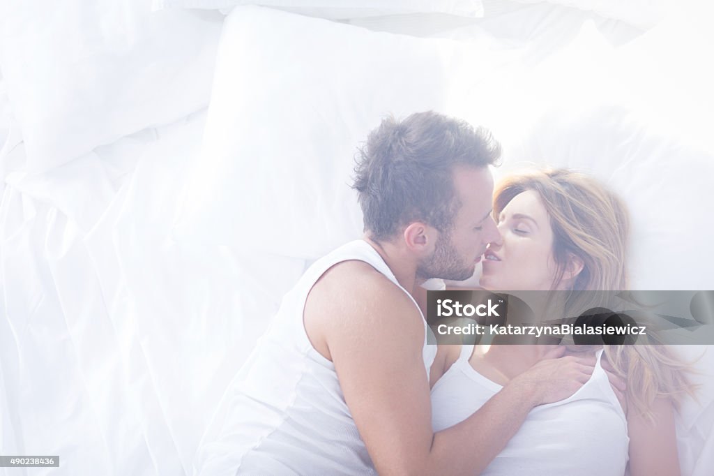 Romantic lovers kissing in bed Picture of two romantic lovers kissing in bed Passion Stock Photo
