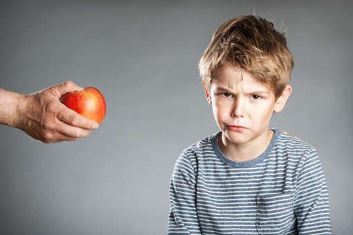 Portrait of boy, hand with apple, refused, grey background