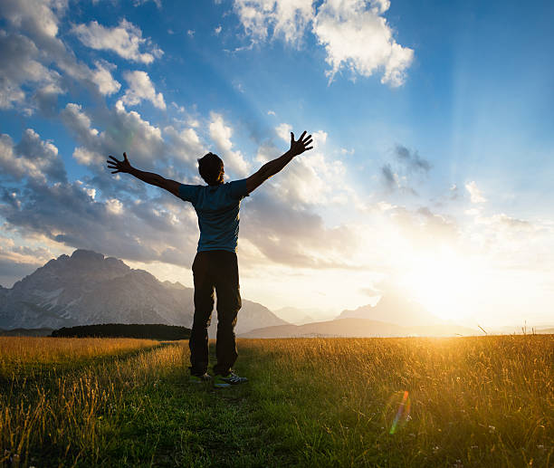 istock Man outstretching his arms on a sunlit meadow at sunset 490242700