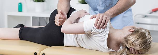 Physiotherapist at work Physiotherapist is rehabilitating young woman back in medical office chiropractic adjustment photos stock pictures, royalty-free photos & images
