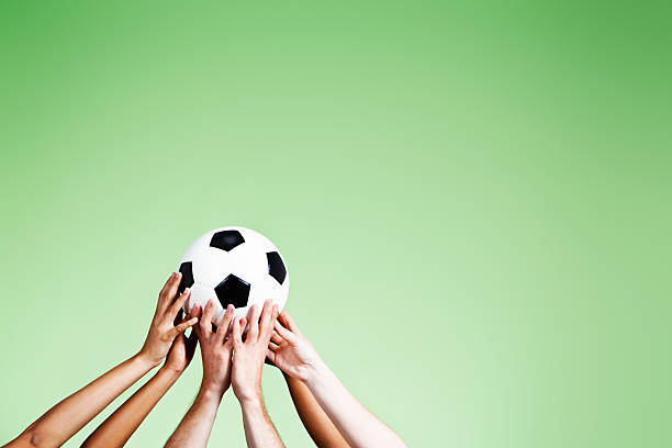 istock The beautiful game! Many hands supporting soccer ball against green 490261577