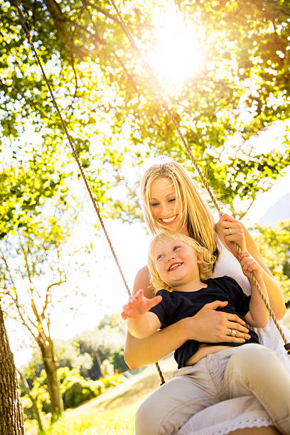 istock Mom and son on swing in park 490261889