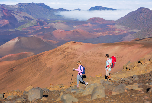Hikers enjoying walk on amazing mountain trail. Backpacking in Haleakala volcano, incredible view. Couple trekking.
