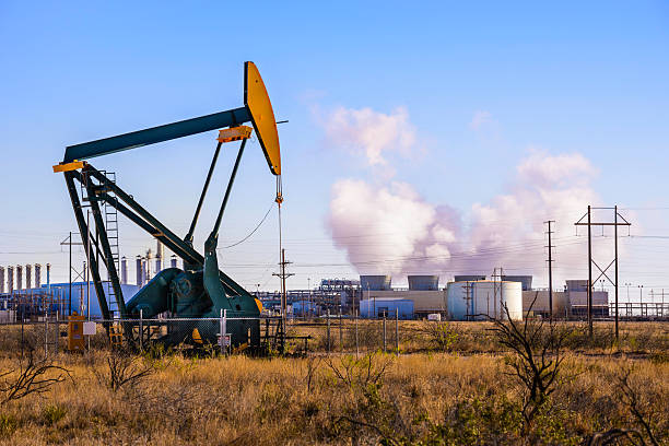 Pumpjack (oil derrick) and refinery power plant in West Texas A pumpjack (oil derrick) and oil refinery in Seminole, West Texas. natural gas extraction stock pictures, royalty-free photos & images