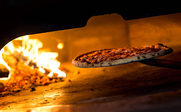 Wood Burning Oven Pizza A pizza is removed from a wood burning oven in a classic Italian restaurant adobe material photos stock pictures, royalty-free photos & images