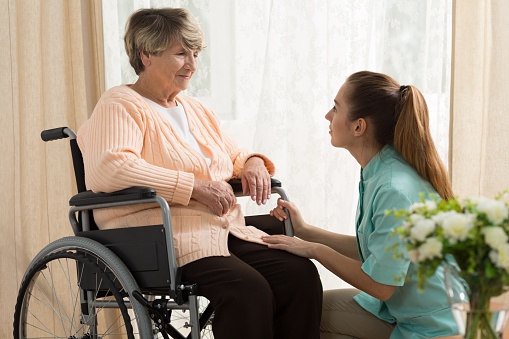 Picture of caregiver helping old female on wheelchair
