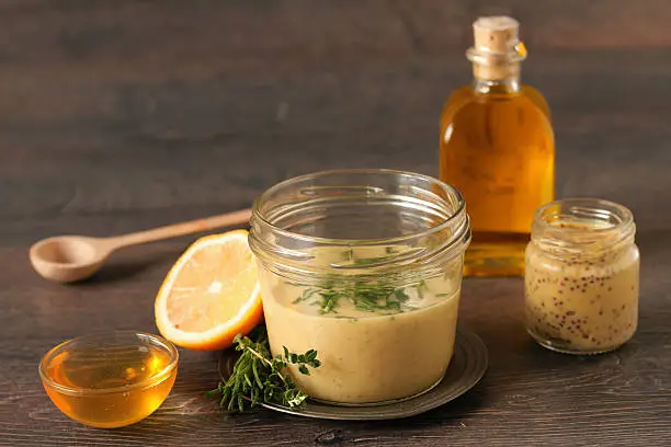 Homemade honey mustard dressing on wooden table