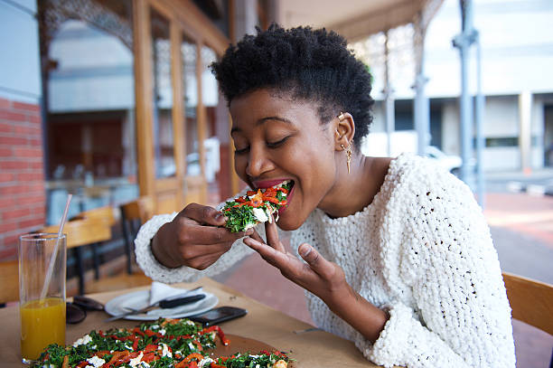 african american kobieta jedzenie pizza na zewnątrz restauracji - eating food biting pizza zdjęcia i obrazy z banku zdjęć