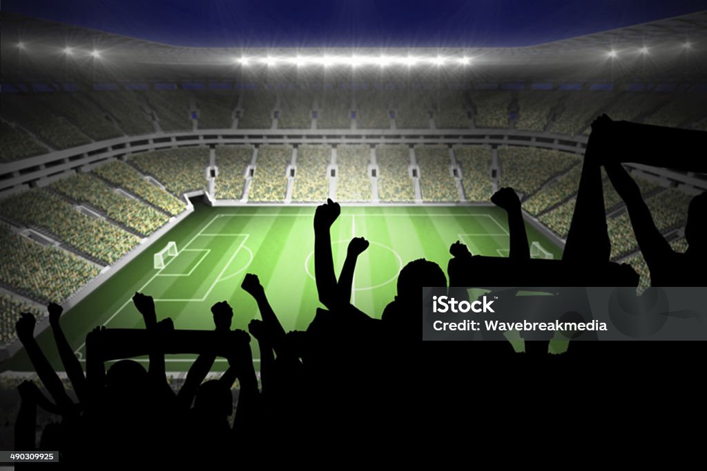 Silhouettes of football supporters Silhouettes of football supporters against large football stadium with lights Soccer Stock Photo