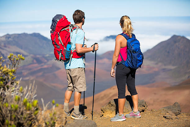 Two hikers relaxing enjoying the amazing view from the mountain top. Looking out over the volcano crater.