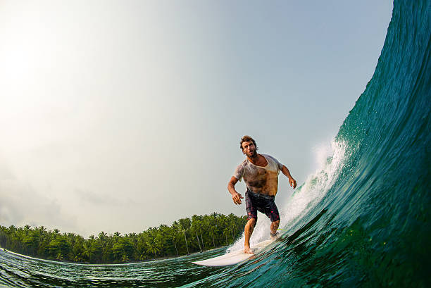 Surfing In Paradise A young male surfer rides a perfect wave in the tropics. Mentawai Islands stock pictures, royalty-free photos & images