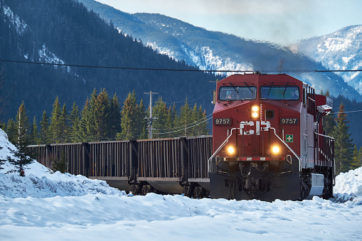 Banff, Canada - March 18, 2014: Canadian Pacific train coming round the bend with Canadian Rockies in the background in winter.