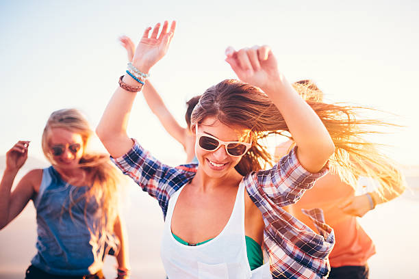 Friends dancing on beach in sunset