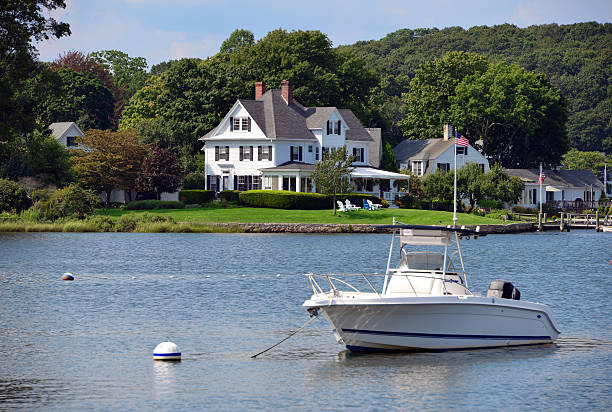 Waterfront luxury house Luxury house on the water's edge - boat and trees. promenade stock pictures, royalty-free photos & images