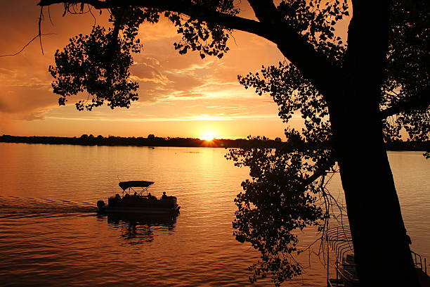 Sunset Pontoon Ride Pontoon cruising a lake at sunset pontoon boat stock pictures, royalty-free photos & images