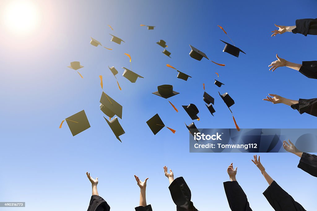 happy young graduates throwing hats happy young graduates throwing hats with blue sky Graduation Stock Photo