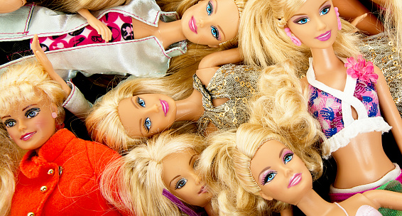 Albuquerque, USA - June 15, 2012:  Studio shot of a pile of Barbie fashion dolls. Barbie dolls are have been manufactured by Mattel, Inc. since1959. Barbie dolls are often a subject of criticisms since she promotes an unrealistic idea of body image for a young woman, leading to a risk that girls who attempt to emulate her look will become anorexic.