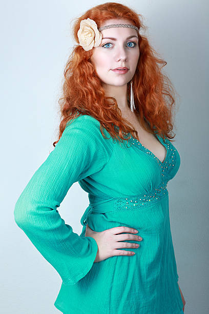 beautiful woman turquoise dress portrait of a beautiful woman with red curly hair. wearing a romantic green or turquoise dress. Fashion blue toning plus size boho clothing stock pictures, royalty-free photos & images
