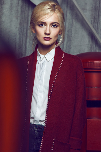 Close up of beautiful young blond woman wearing long red coat.