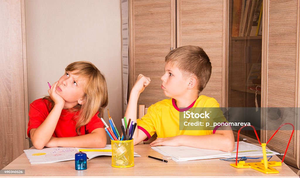 Children quarreling while doing homework together. Conflict Stock Photo