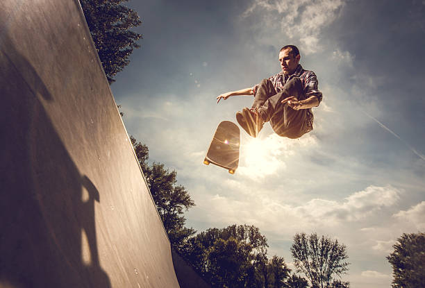 Low angle view of a young man skateboarding outdoors. Below view of an extreme man skateboarding at the park. x games stock pictures, royalty-free photos & images