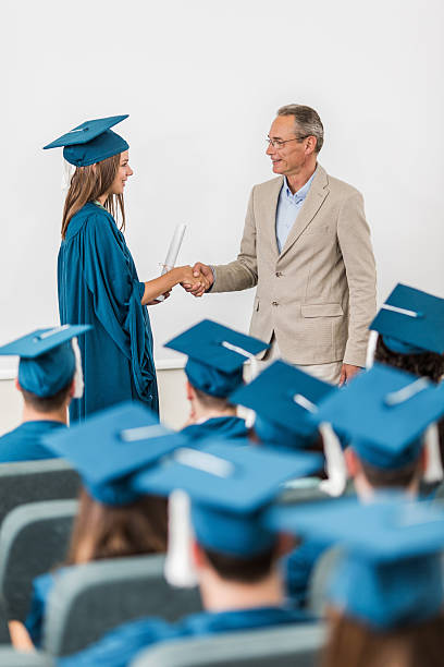 istock Graduation student receiving diploma and shaking hands with professor. 490349642