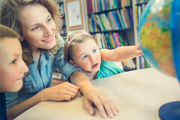 istock Education. Side view of little kids pointing at globe. 490359130
