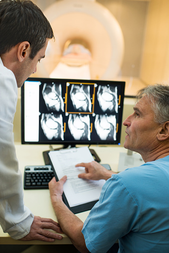 Doctor talking to a mature radiologist who holding medical chart.