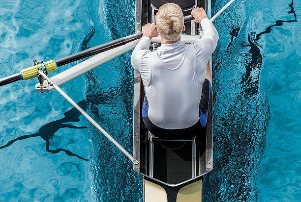 Rower top view Top view of athletic competition rower, who strokes his  paddle through metallic blue water. rowing stock pictures, royalty-free photos & images