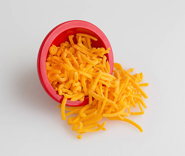 istock Bowl of shredded sharp cheddar cheese spilling on cutting board 490365882