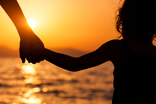 Children standing on beach at sunset.