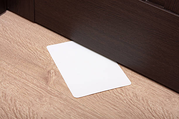 white envelope with message slipped under wooden door. stock photo