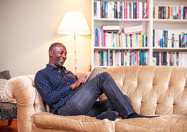 istock Smiling mature man with digital tablet in living room 490380473