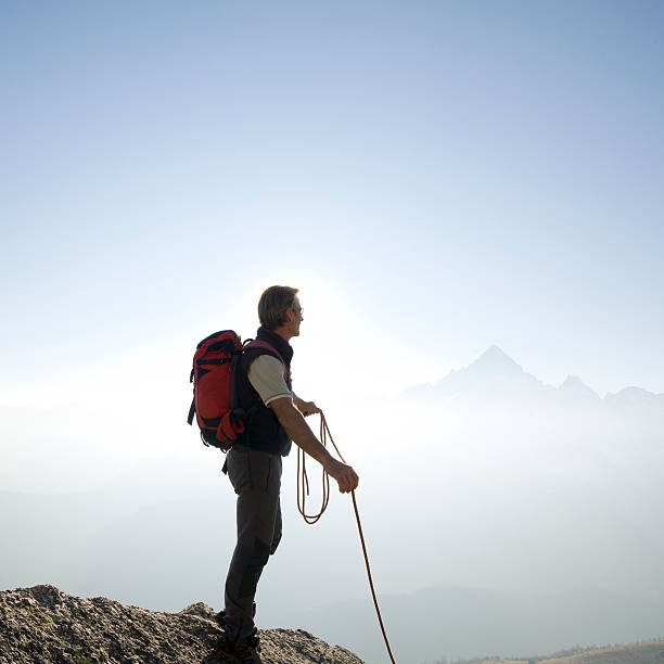 istock Climber stands holding rope on mountain summit 490388900