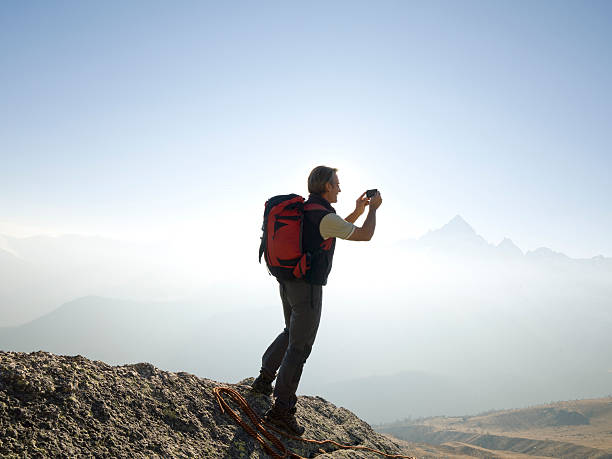 istock Climber stands taking picture on mountain summit 490389108