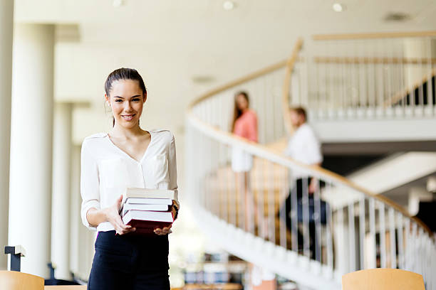 istock Beautiful woman holding books in a library 490393438