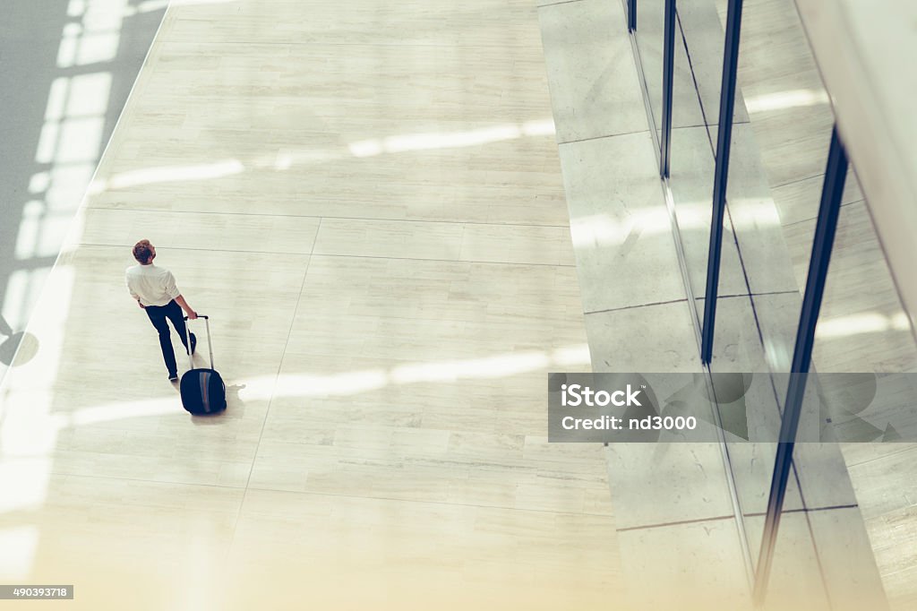 Handsome business holding a trolley Handsome business holding a trolley and walking in a modern building seen from above Business Travel Stock Photo