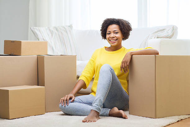 feliz mujer africana con cajas de cartón en su casa - women sofa teenage girls hairstyle fotografías e imágenes de stock