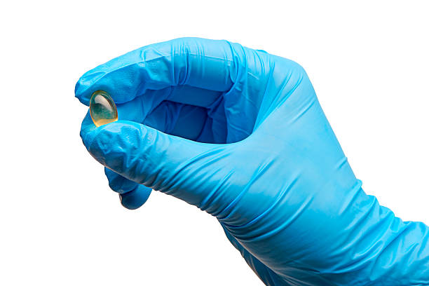 arzt hand in blaue zubehör op-handschuhe holding tablet - surgical glove human hand holding capsule stock-fotos und bilder