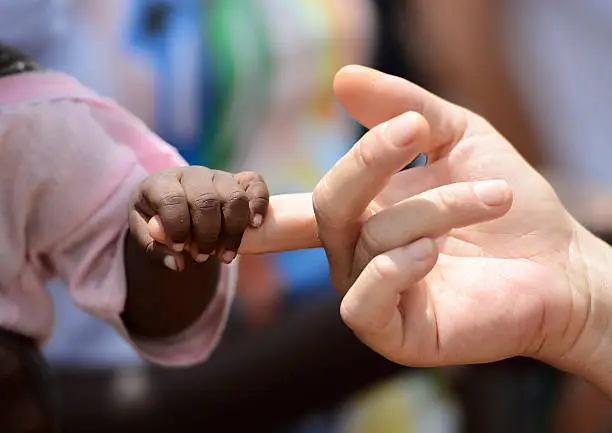 Photo of Black Baby and White Woman Holding Hands Fingers Africa