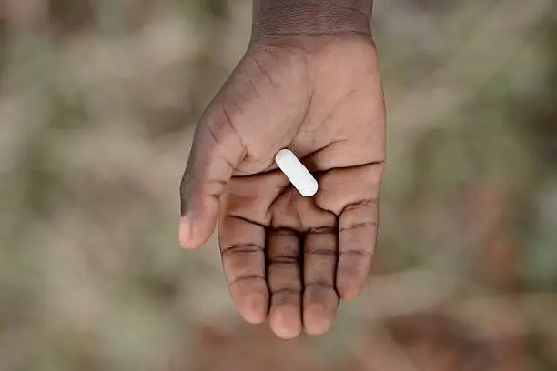Medicine Healthcare Symbol. Black African girl holding pills to cure diseases. Unfortunately, in Africa there are lots of diseases like malaria, pneumonia, AIDS or simple Diarrhoea. Thereforem, medicine and healthcare pills are very important in the black continent.