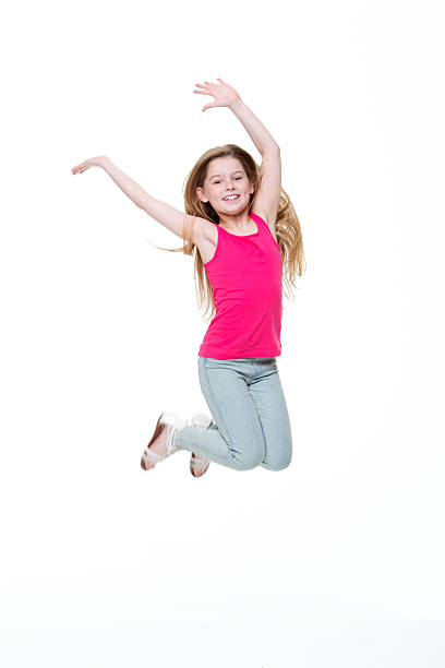Playful teen drummer girl playing with her drumstick while jumping against white background