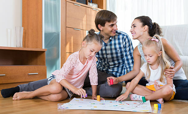 istock girls playing with parents at board game on floor 490400182