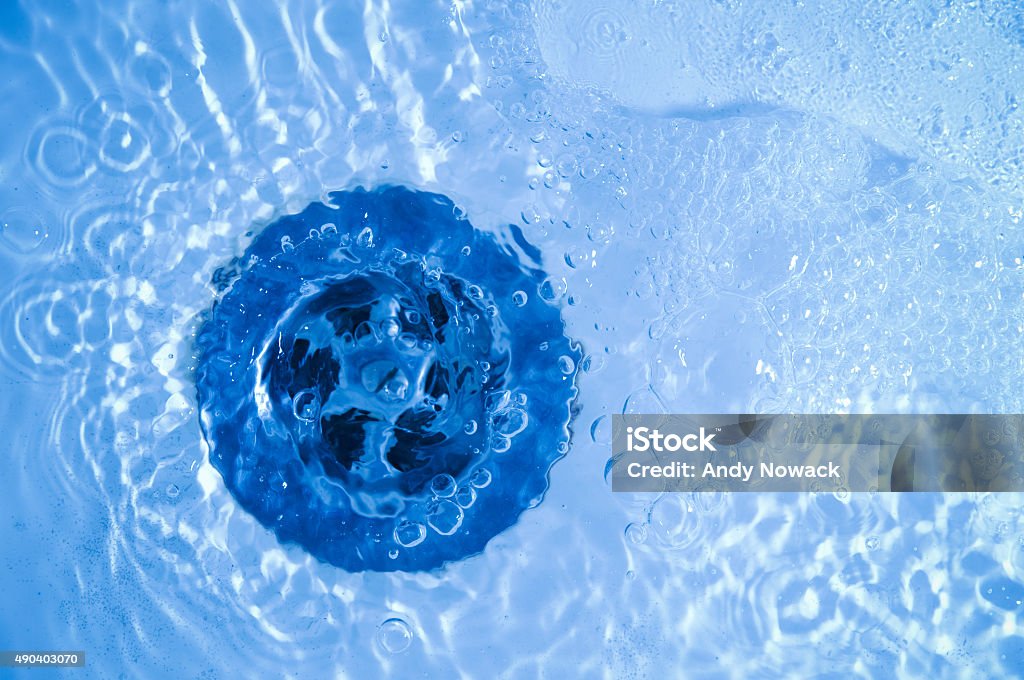 olutlet in blue Close-up of bath tub sink with water running away Bathtub Stock Photo