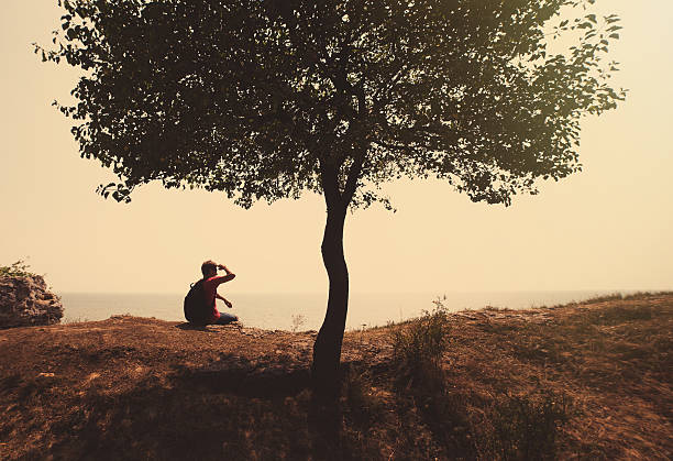 istock Happy man sitting on hill near tree 490403132