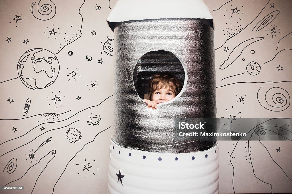 Happy child dressed in an astronaut costume Happy child playing with big hand made rocket. Child Stock Photo