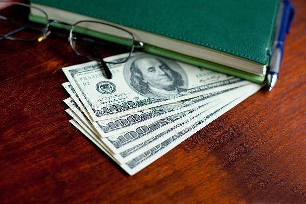 istock Stacks of one hundred dollars banknotes, notebook, pen and glasses 490450749