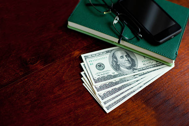 istock Stacks of one hundred dollars banknotes, notebook, mobilephone and glasses 490450771