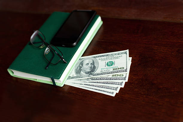 istock Stacks of one hundred dollars banknotes, notebook, mobilephone and glasses 490450795